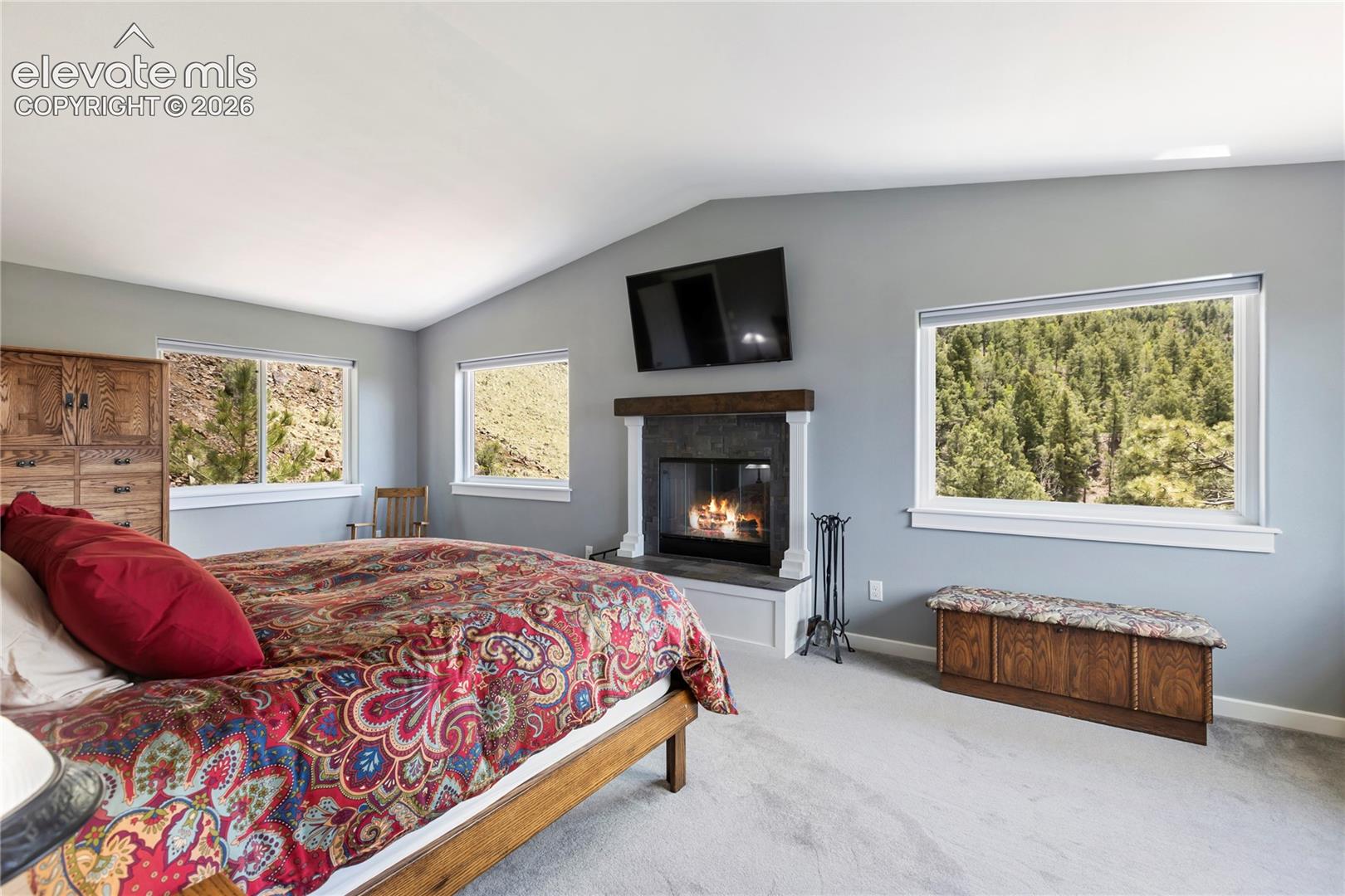 Primary bedroom with a wood burning fireplace and plenty of views!