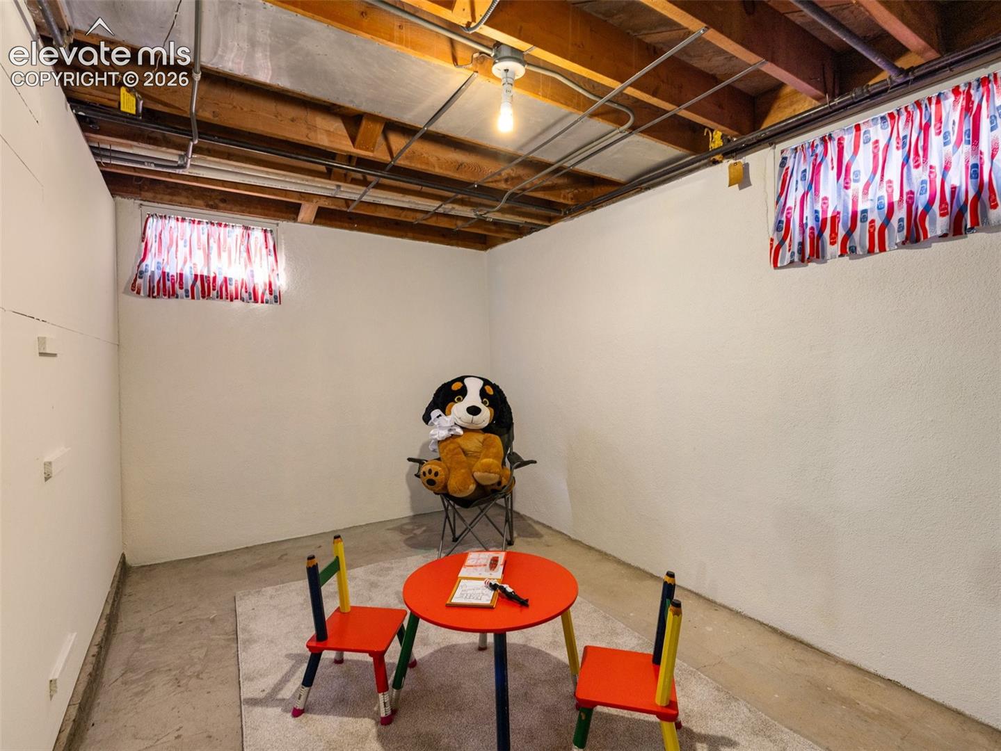 Unfinished lower level featuring exposed wood joist ceilings, painted concrete walls, concrete flooring, and two recessed windows