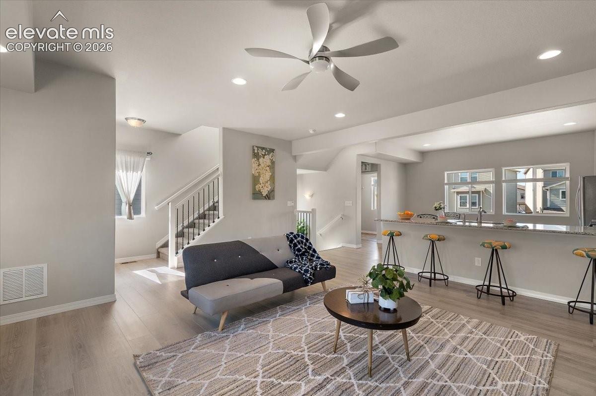 Open-concept living space with wood-finish flooring, recessed lighting, and a ceiling fan