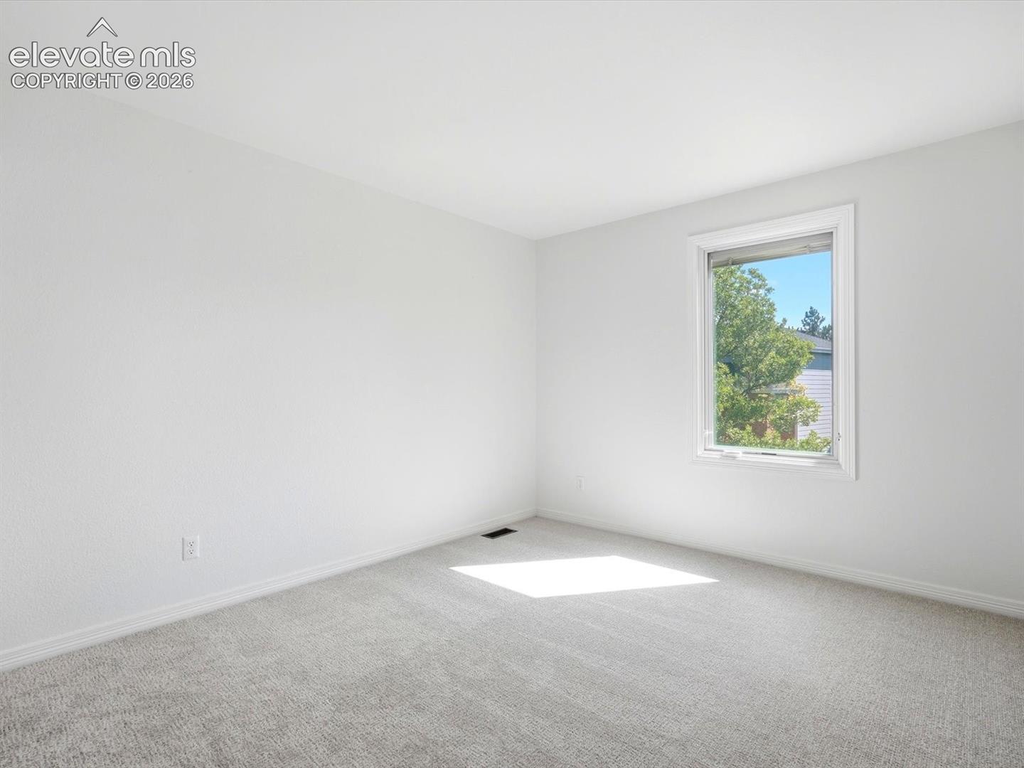 Neutral-toned wall-to-wall carpeting and single-pane window with white trim