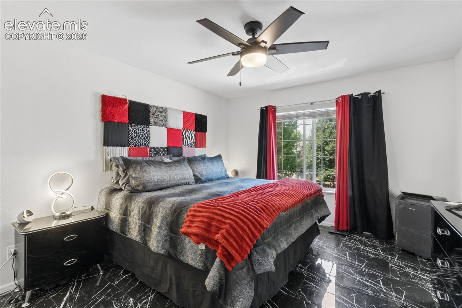 Black marble-look tile flooring, white walls, and a window with a metal grid