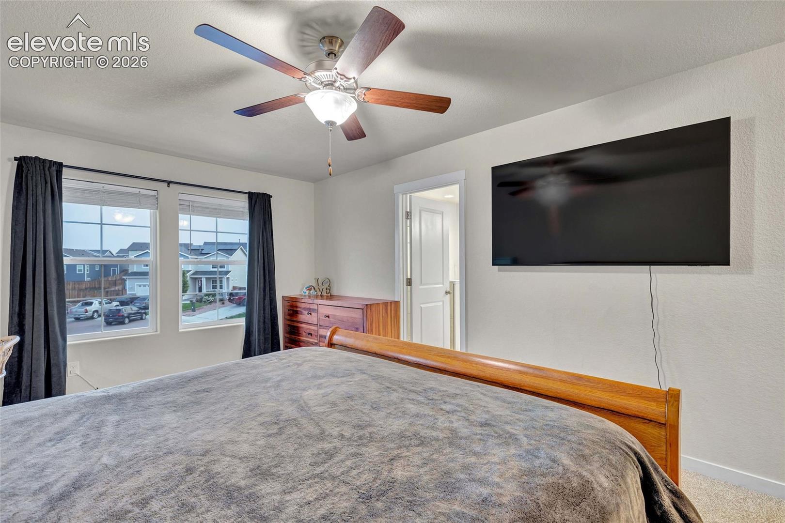 Dual pane windows, ceiling fan with integrated lighting, wall-mounted television, and carpeted flooring