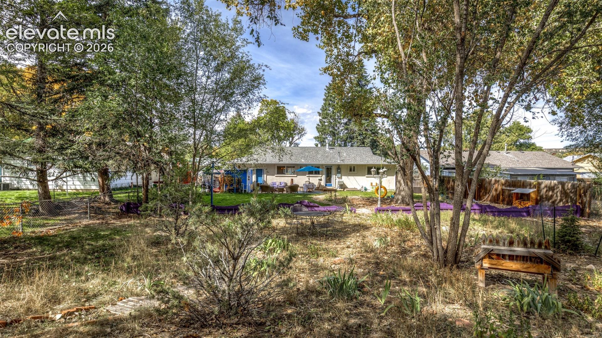 Expansive backyard with a manicured lawn, mature trees, and an exterior patio area