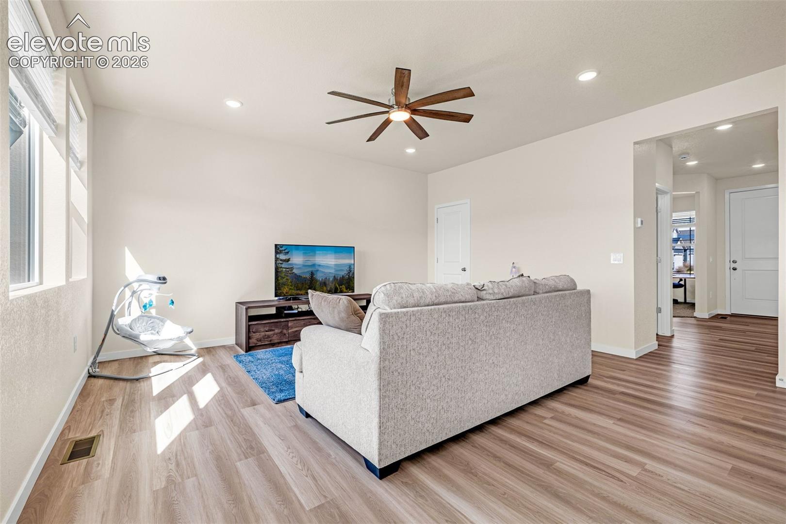Warm wood-finish flooring, recessed lighting, and a ceiling fan with wood-look blades