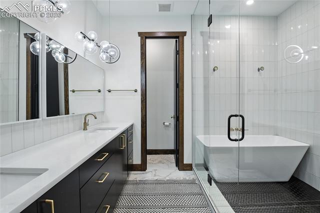 Full bathroom featuring a shower stall, double vanity, and a freestanding bath