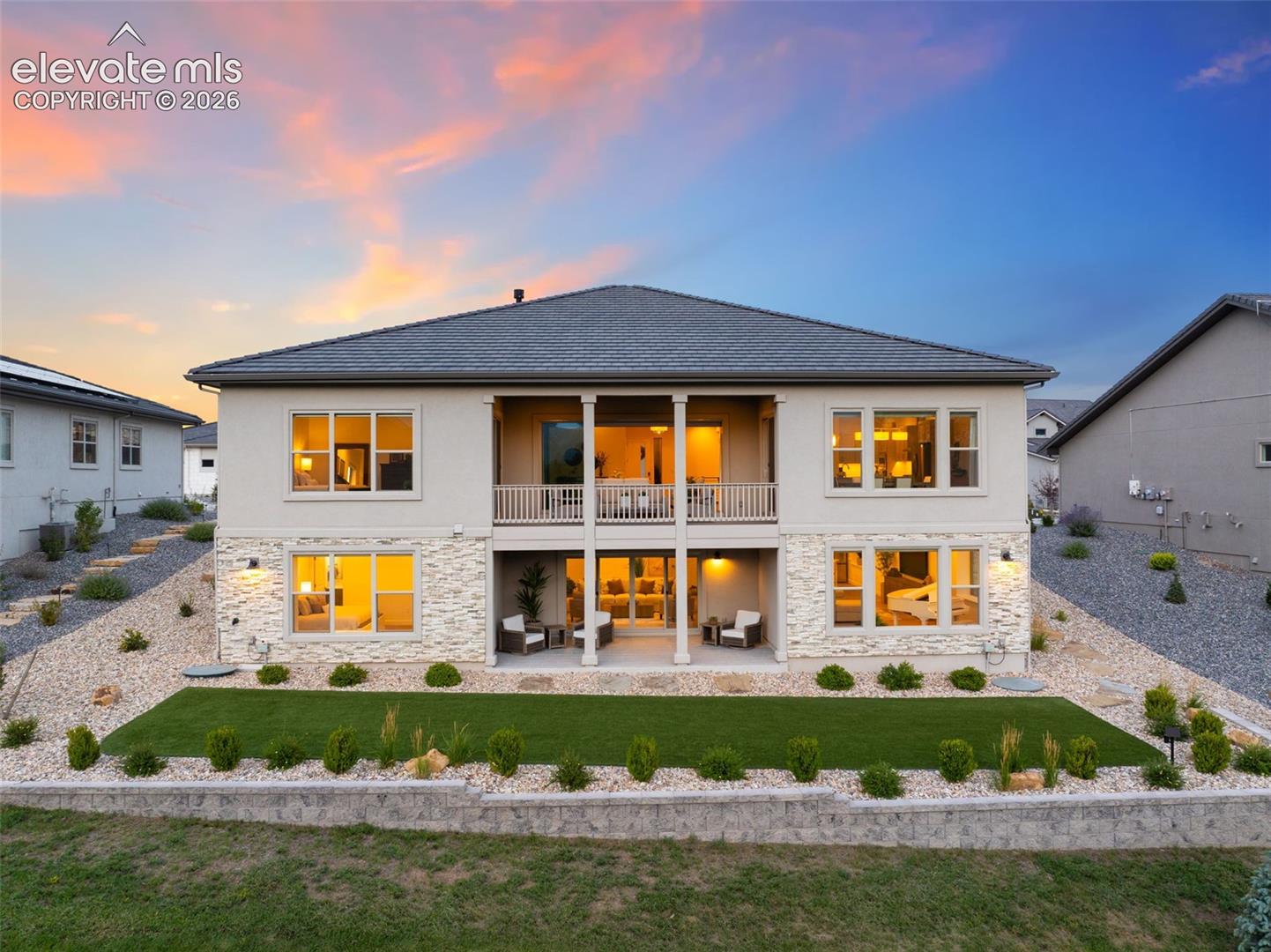Stucco exterior with stone accents, a covered balcony, and a covered patio
