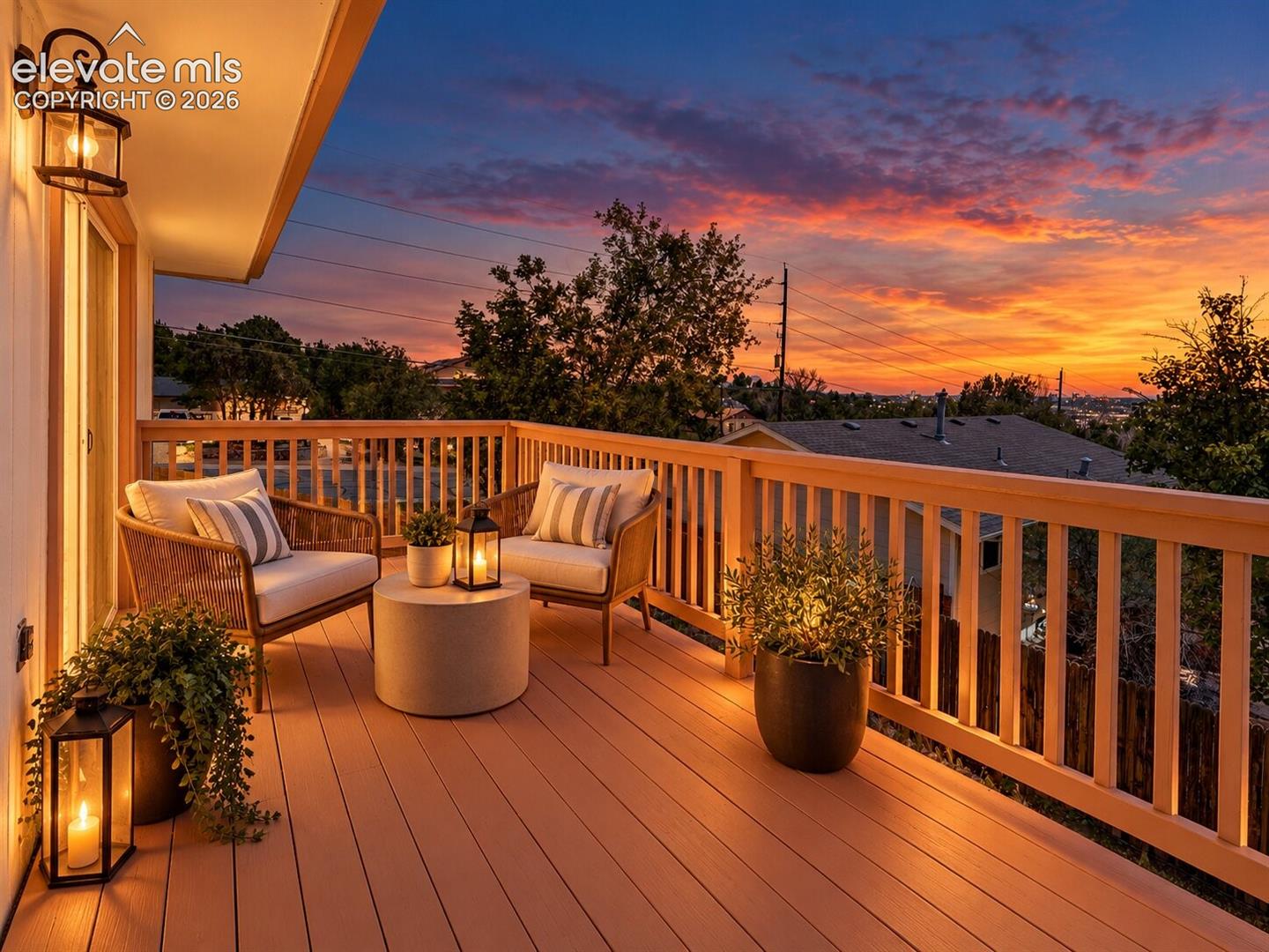 Covered outdoor balcony featuring composite decking, wooden railings, and mounted wall lighting. AI-Enhanced – furniture/decor digitally added