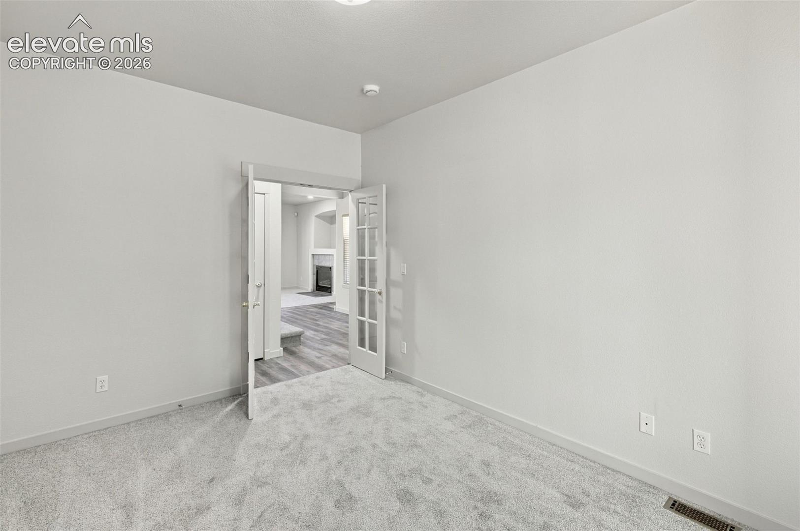 Interior room featuring wall-to-wall carpeting and neutral wall paint, highlighted by double French doors with glass panes