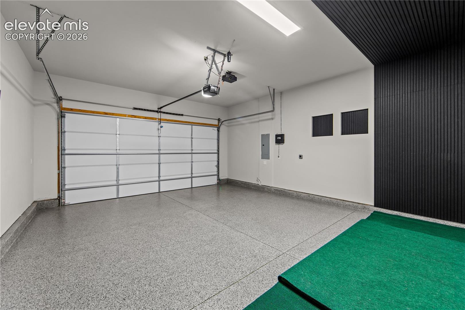Finished garage featuring epoxy flooring, textured dark accent wall, and automated sectional overhead door