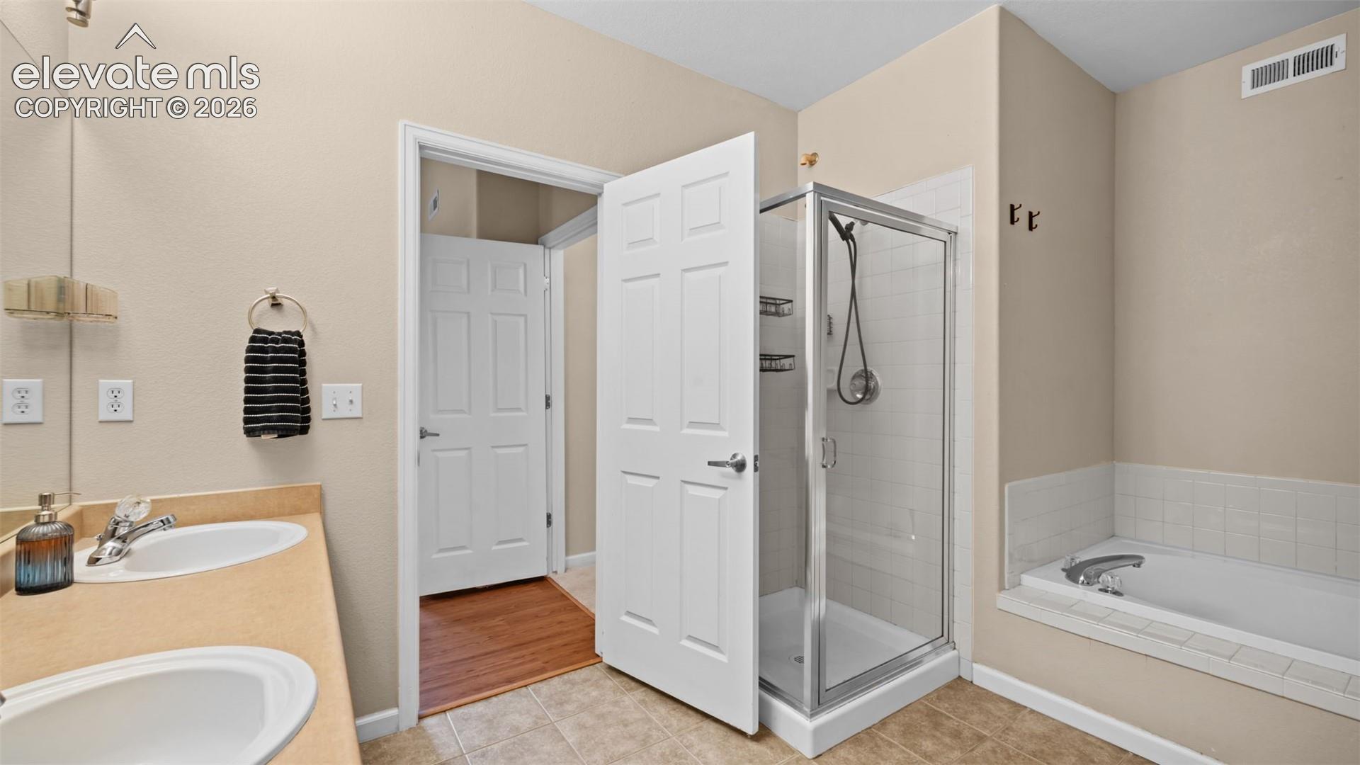 Dual vanity with undermount sinks, a glass-enclosed shower, and a built-in soaking tub
