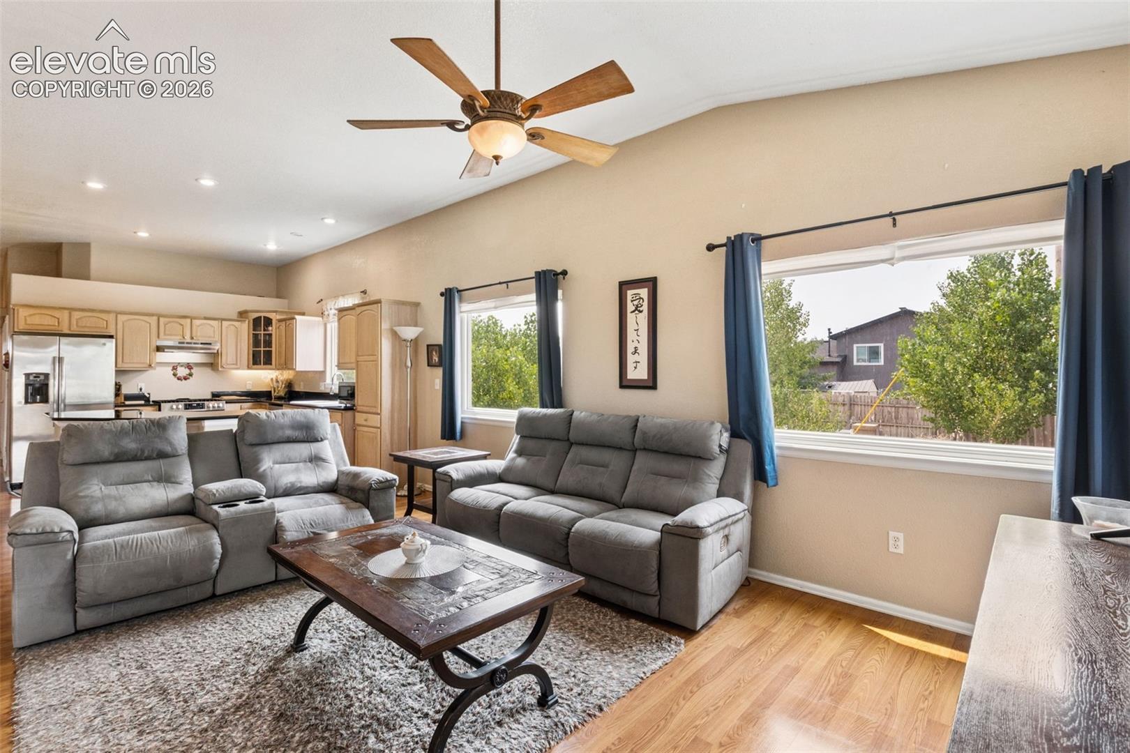 Vaulted ceilings featuring a central paddle fan, wood-finish flooring, and recessed lighting