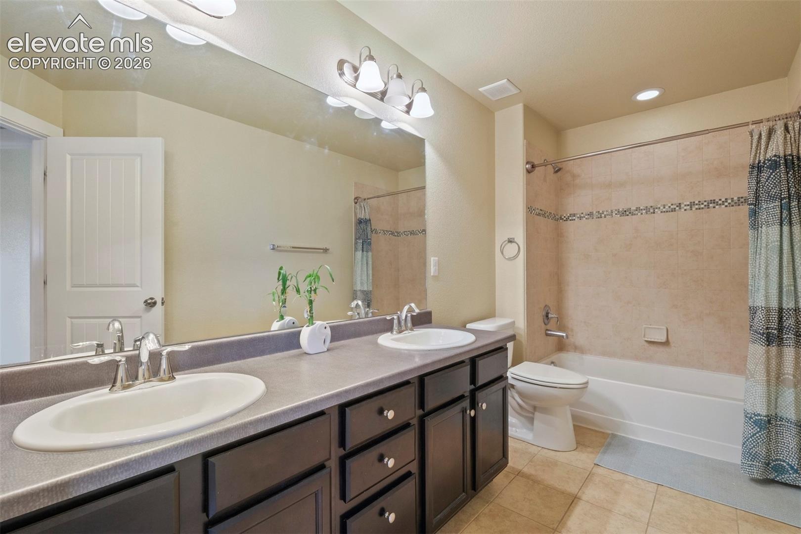 Upper Level: Bathroom featuring a dual vanity with dark wood-finish cabinetry, a full-width mirror, and a tiled shower-tub combination