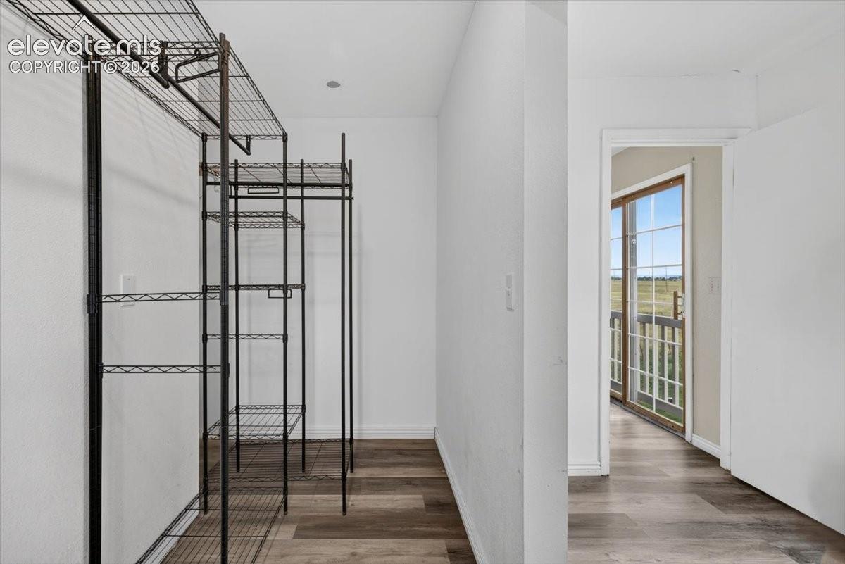Storage area featuring wood-finish flooring and wire shelving, with a sliding glass door providing external access