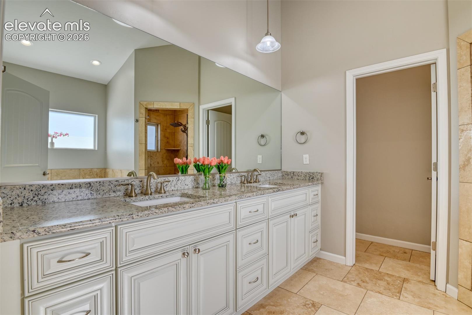 Dual vanity with stone-finish countertop, undermount sinks, and white cabinetry.