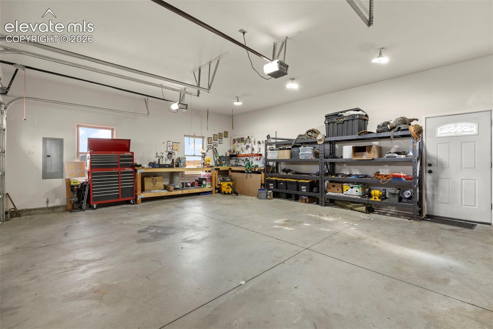 Spacious garage featuring concrete flooring, multiple ceiling-mounted light fixtures, and a side-entry door with an inset window
