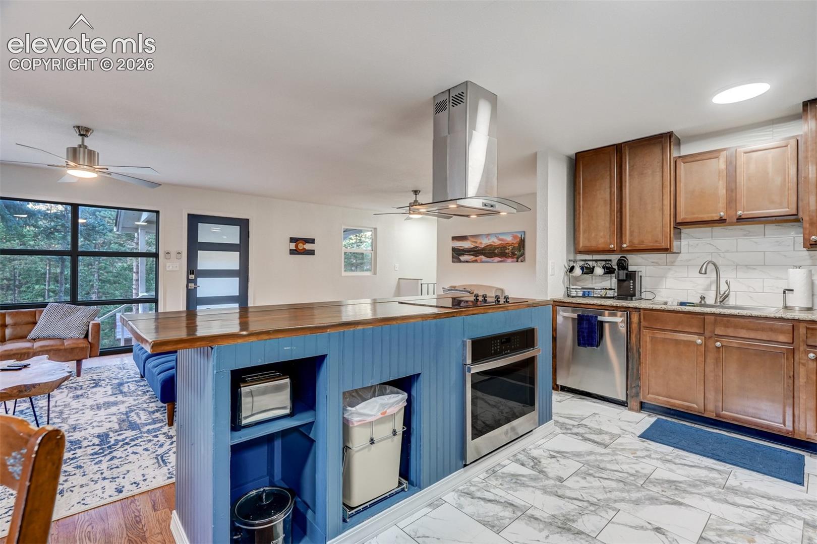 Kitchen featuring a wood-finish island with a blue base, stainless steel appliances, and a tile backsplash