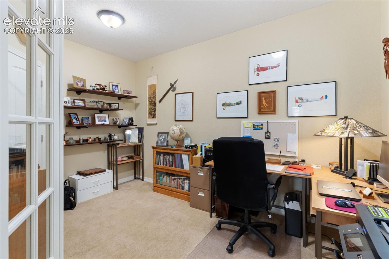 Carpeted room featuring French doors, built-in floating shelves and closet.