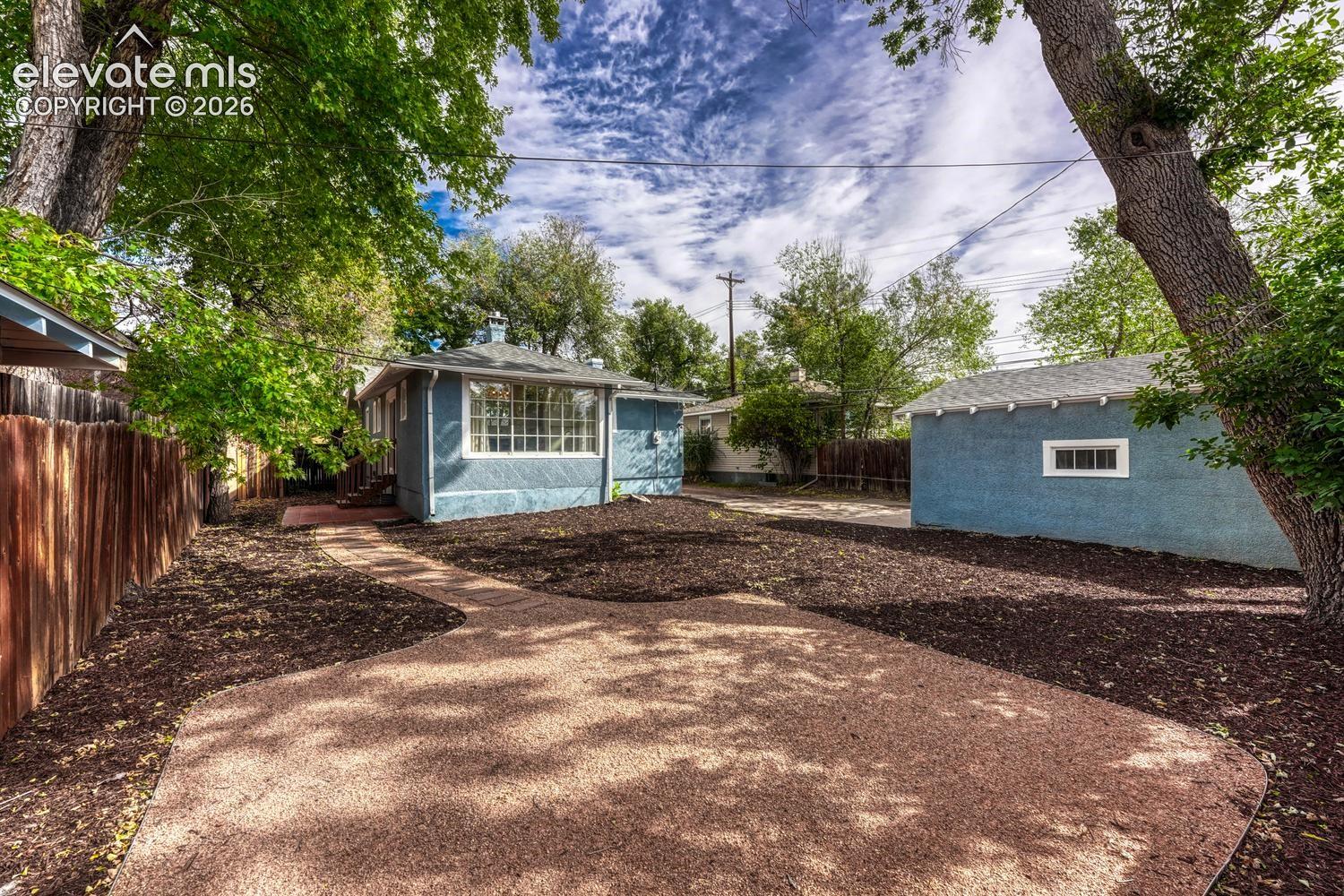 Spacious outdoor area featuring a gravel patio, wood chip landscaping, and mature trees