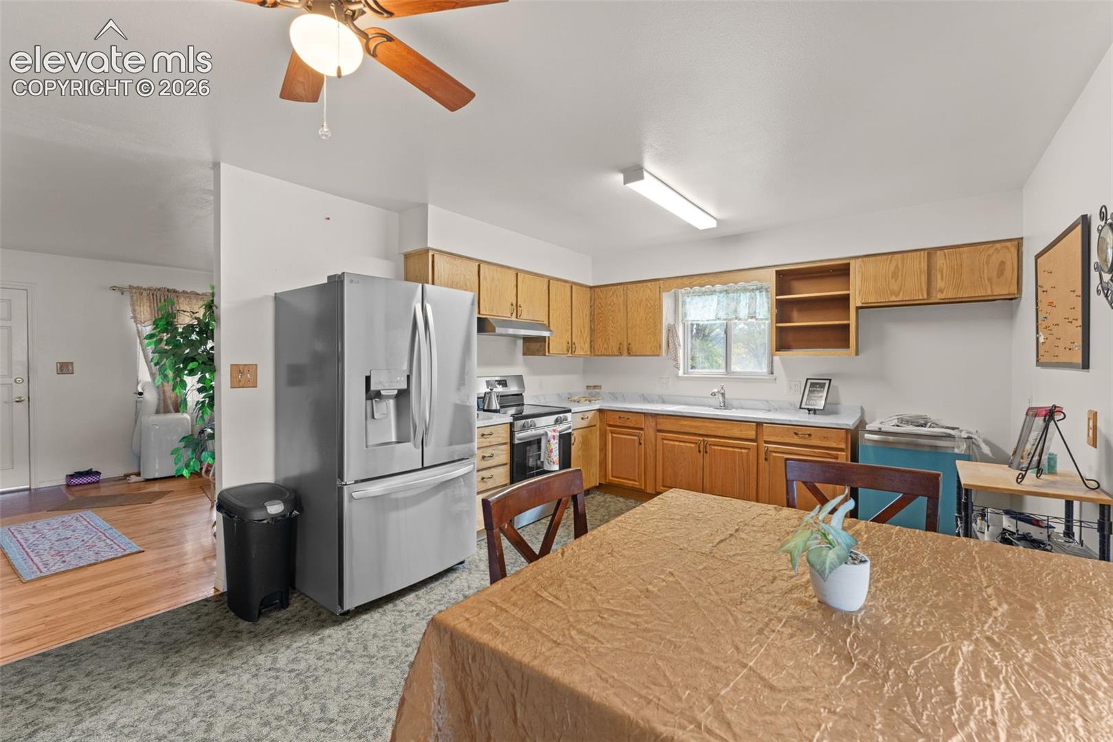 Kitchen featuring wood cabinetry, stainless steel refrigerator, white countertops, and a ceiling fan