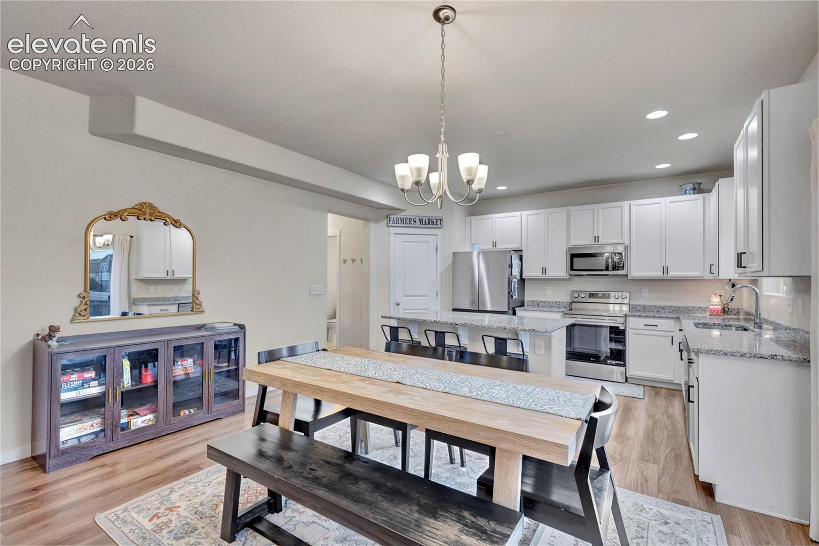 Modern kitchen featuring white cabinetry, stainless steel appliances, granite countertops, and a subway tile backsplash