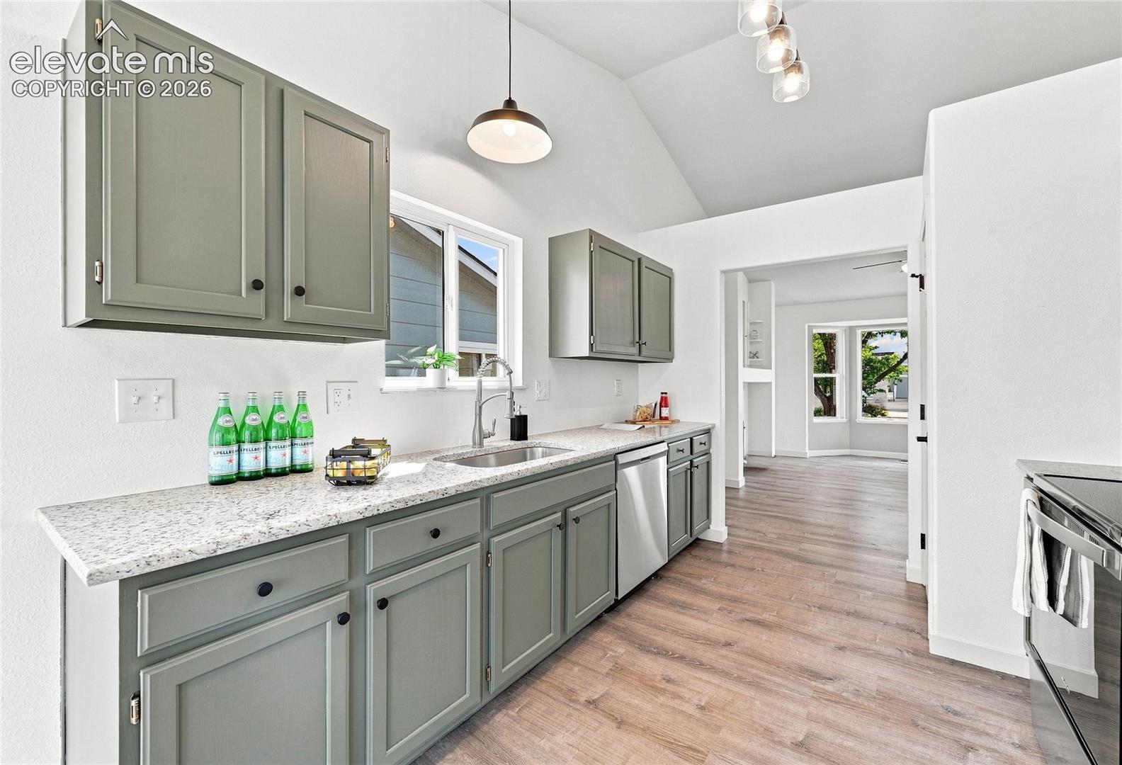 Kitchen featuring wood-finish flooring, gray shaker-style cabinetry, light-toned countertops, and a stainless steel dishwasher