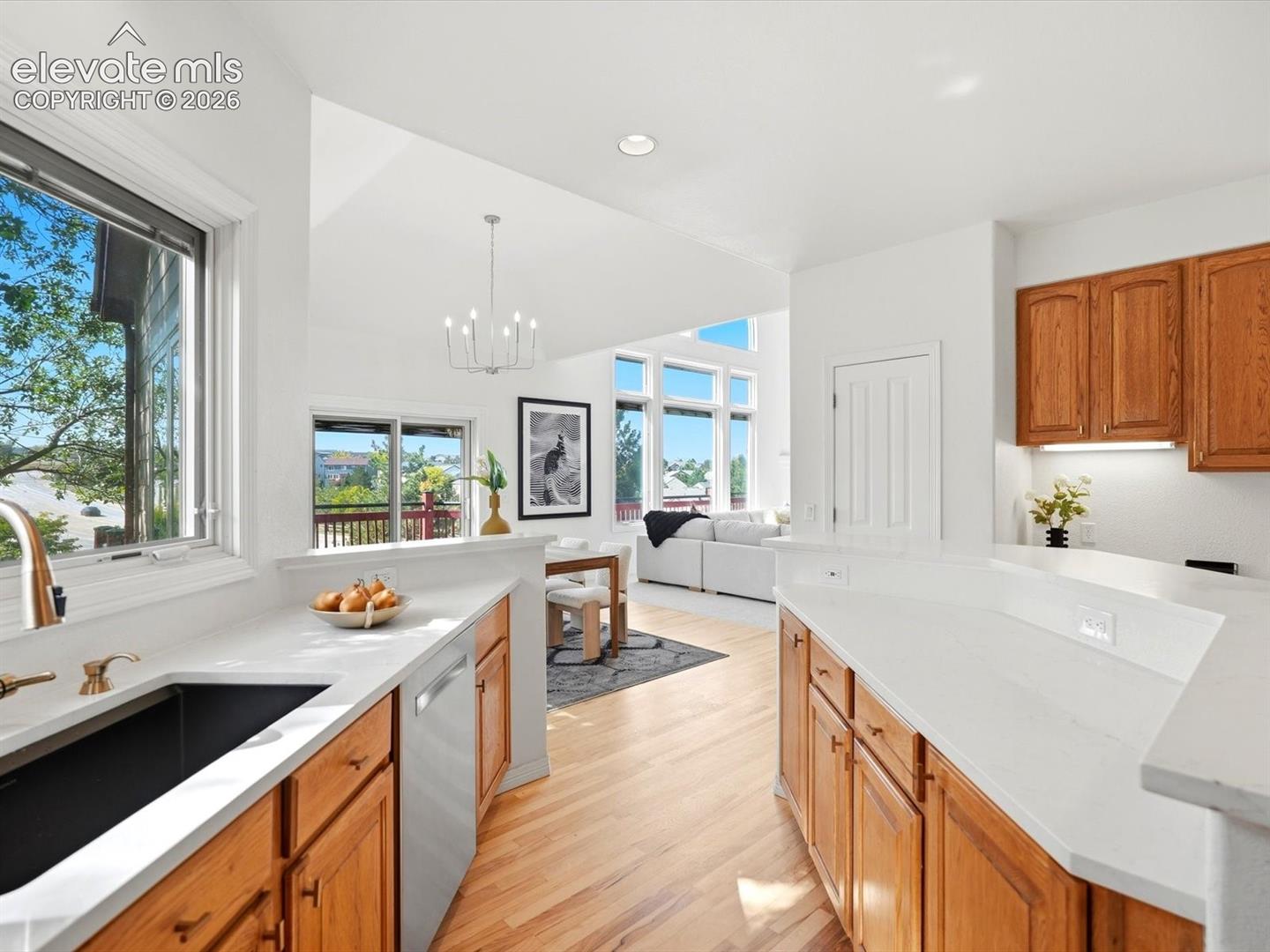 Kitchen featuring wood cabinetry, white countertops, a deep-basin sink with a metallic faucet, stainless steel dishwasher, and wood-finish flooring