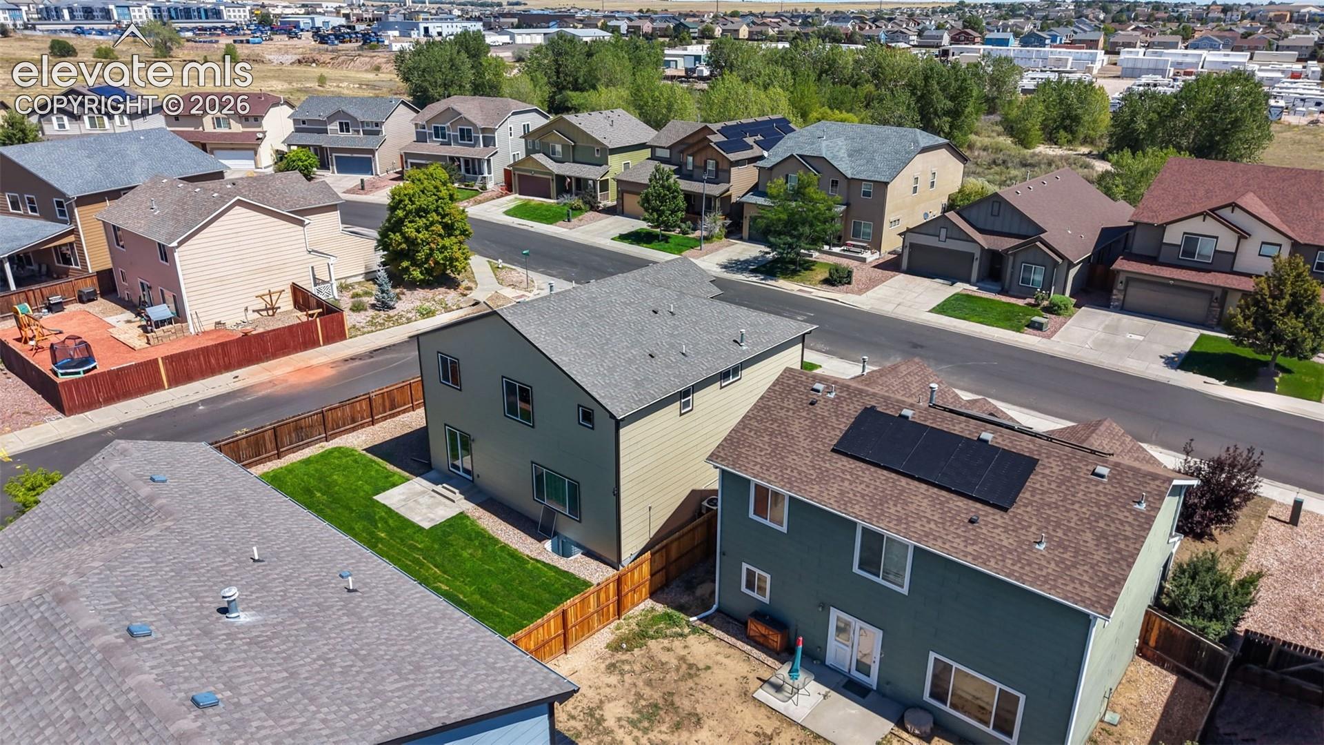 Residential neighborhood with mature trees, two-story homes, and visible rooftop solar panels