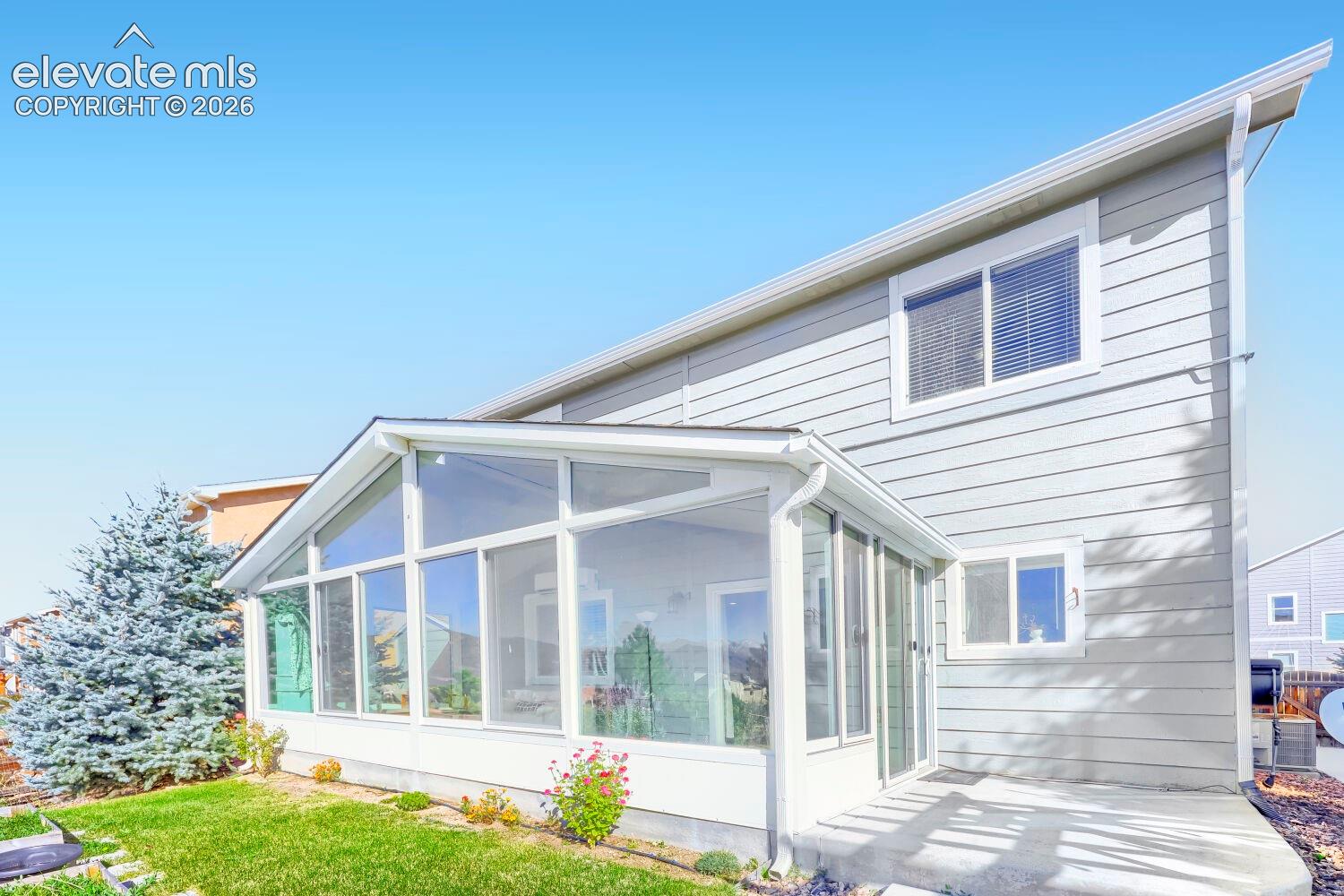 Exterior featuring horizontal siding, a sunroom with expansive windows and sliding glass doors, and a concrete patio
