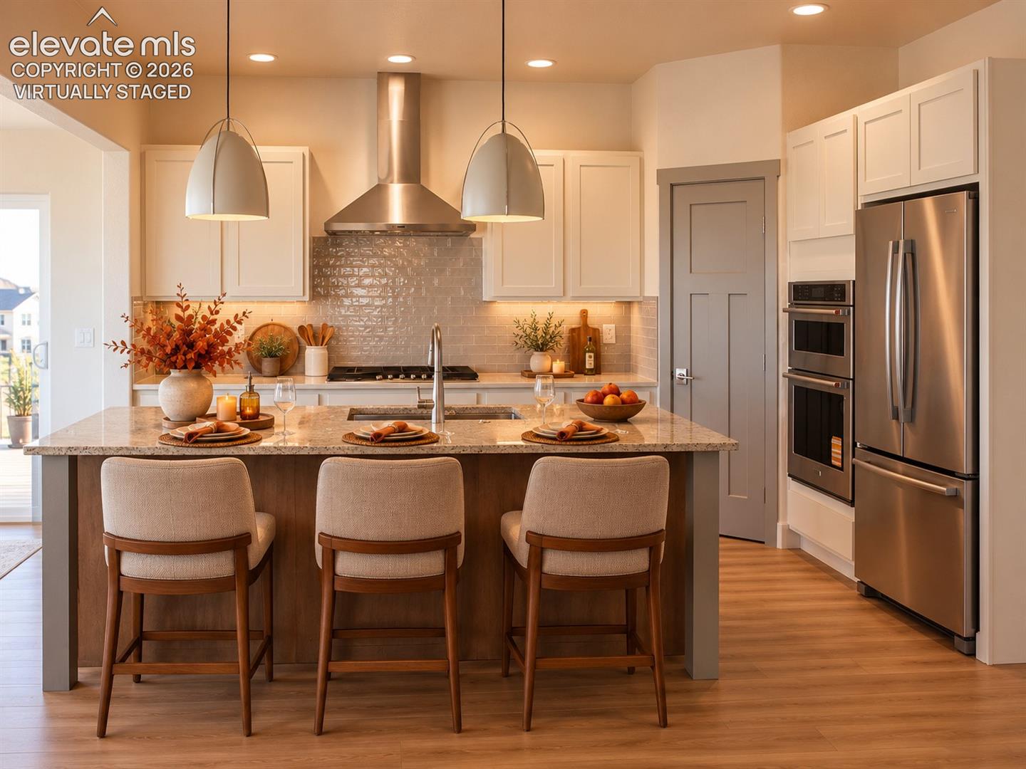 Virtually staged Gourmet kitchen featuring a center island with sink, wood-finish flooring, stainless steel appliances, white cabinetry, and a textured tile backsplash