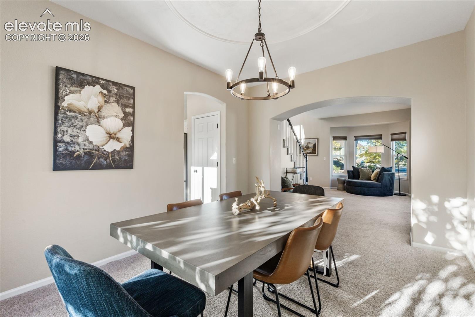 Dining area featuring a circular iron chandelier, intricate ceiling medallion, and arched architectural entryways