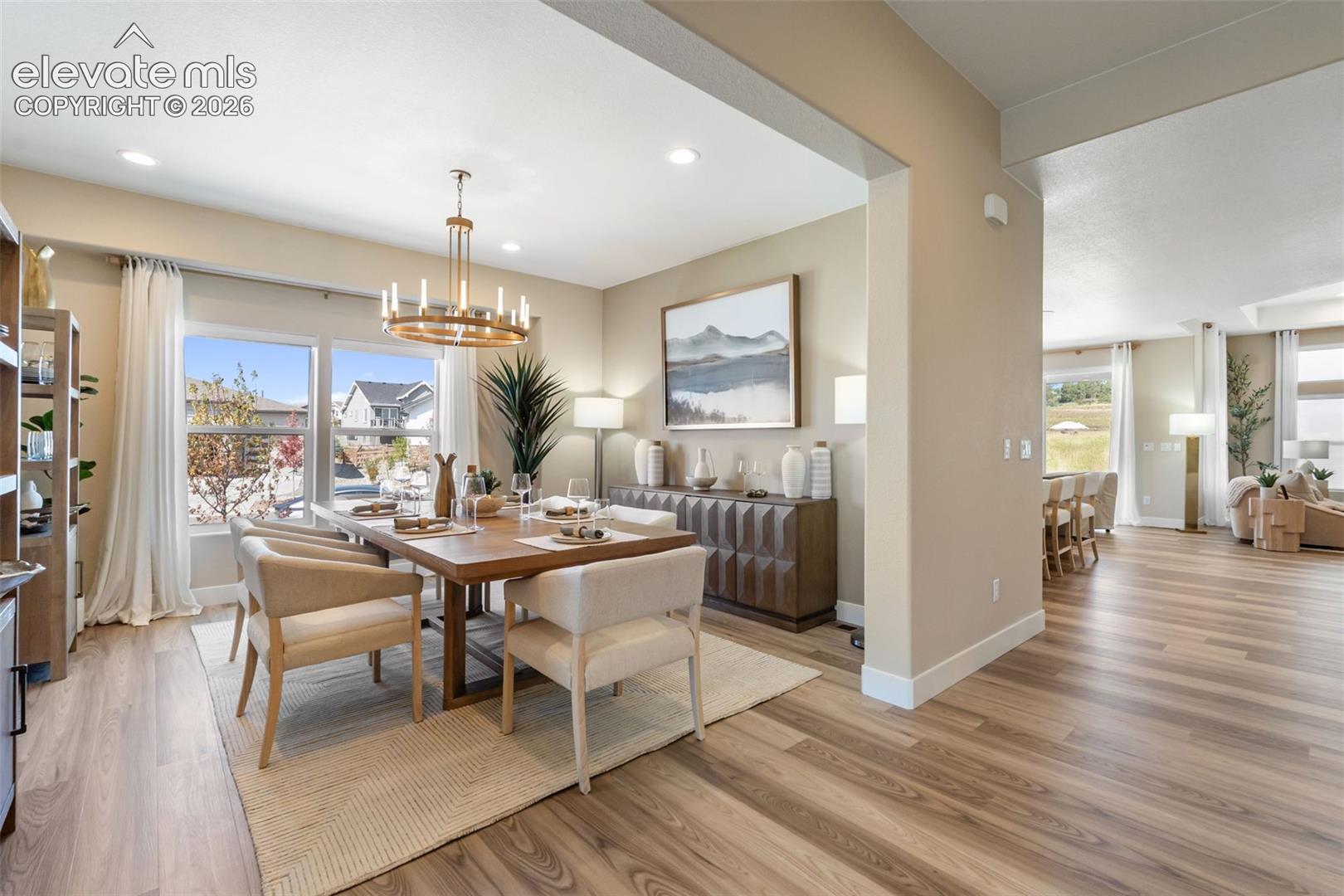 Dining area featuring wood-finish flooring, a metal circular chandelier, large multi-pane windows, and recessed ceiling lighting