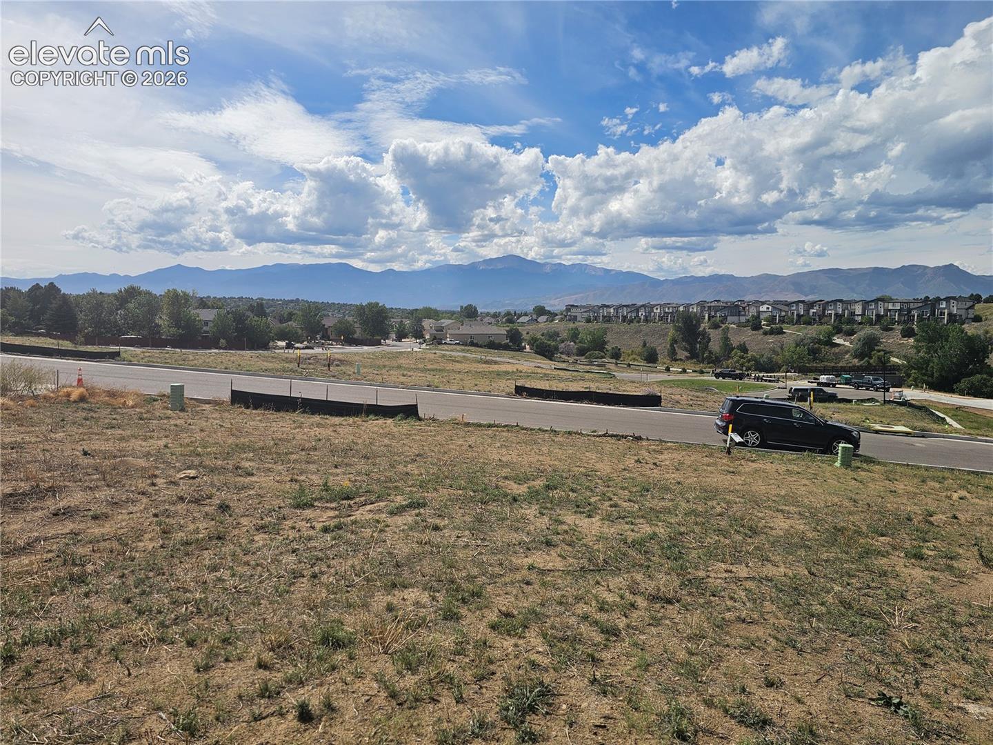 Vacant lot featuring paved street access, native vegetation, and expansive mountain scenery