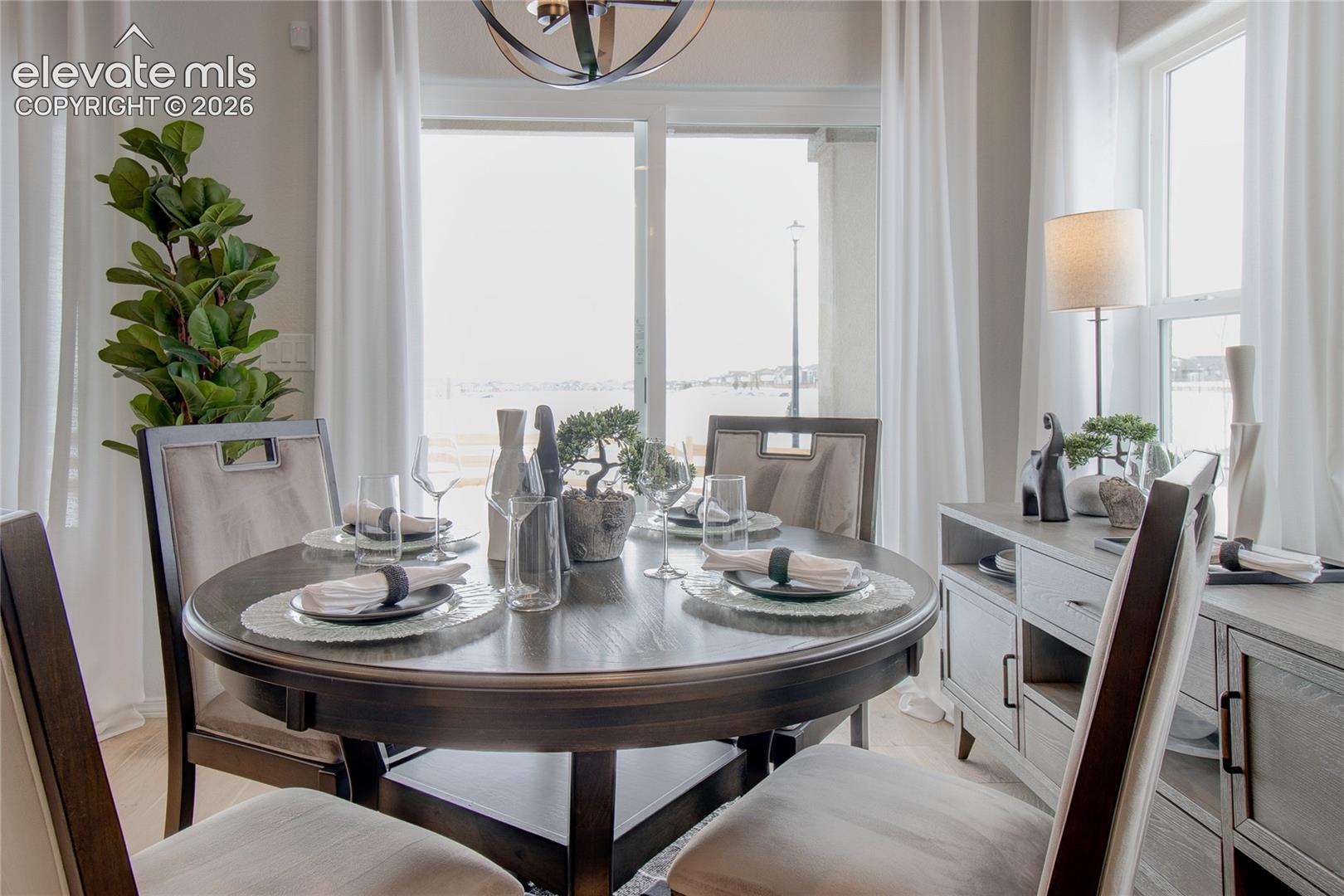 Sliding glass door, spherical metal chandelier, and wood-finish flooring