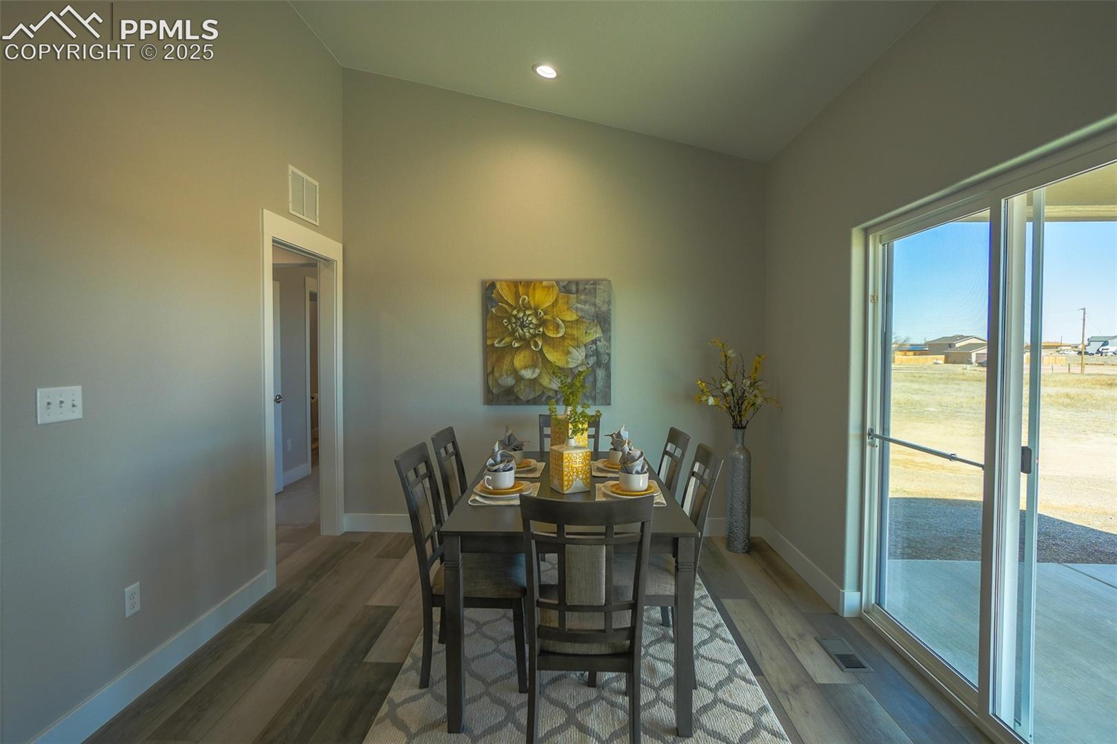 Dining space with LTV/ wood-style floors and vaulted ceiling