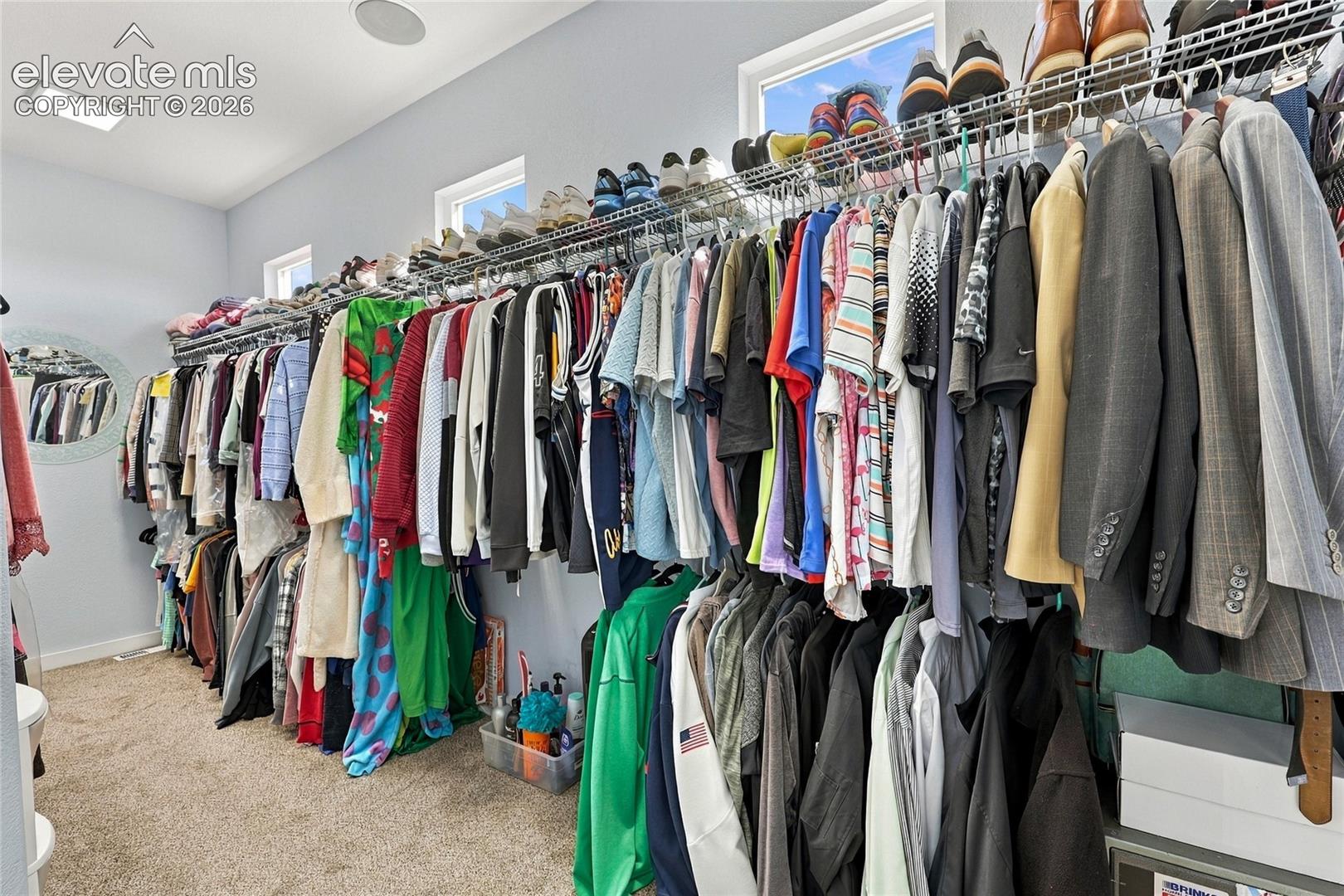 Walk-in closet featuring tiered wire shelving, high-set windows, and recessed ceiling lighting