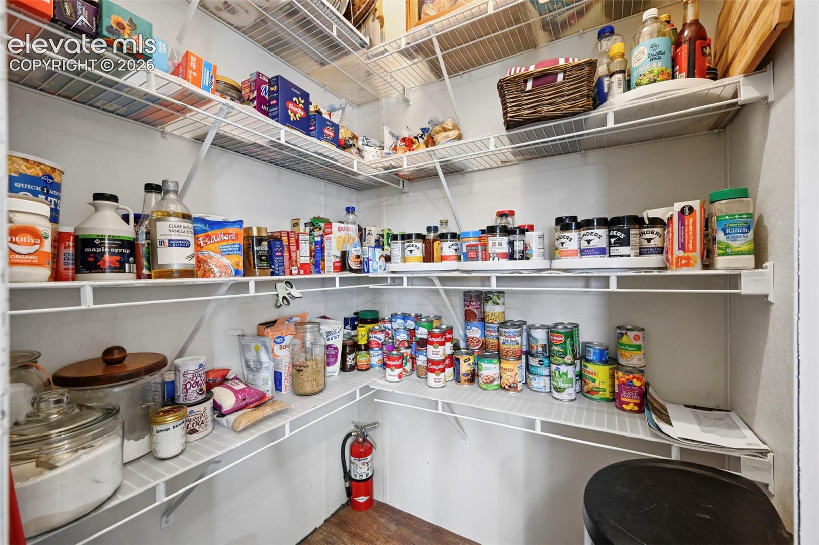 Walk-in pantry featuring multiple levels of white wire shelving and wood-finish flooring
