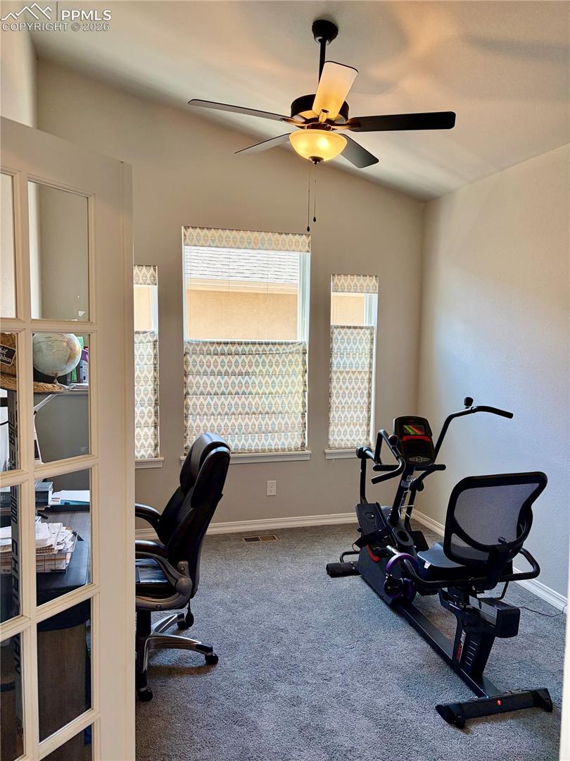 Main level office with ceiling fan and vaulted ceiling