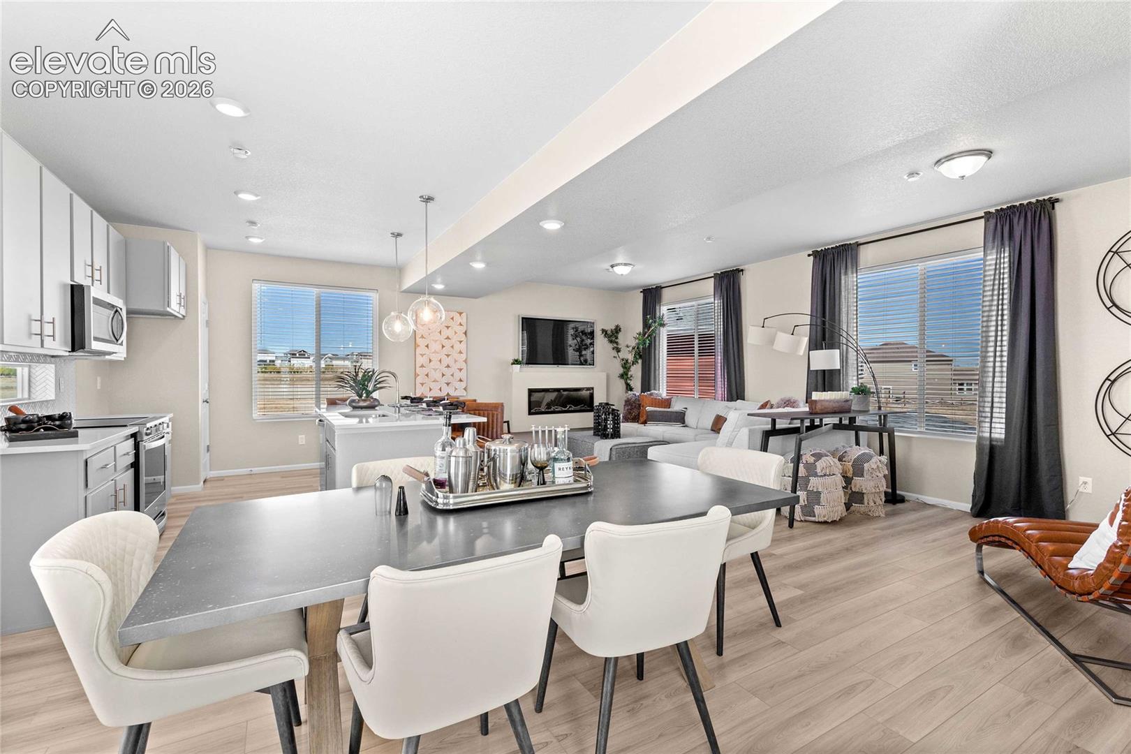 Open-concept living area featuring wood-finish flooring, a kitchen island, a built-in fireplace, and recessed lighting
*photos of a model home*