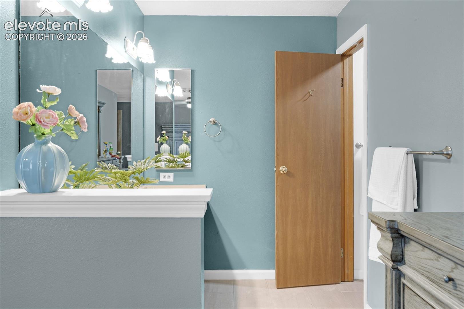 Bathroom vanity area featuring a white-trimmed counter, dual rectangular mirrors, and a three-light fixture