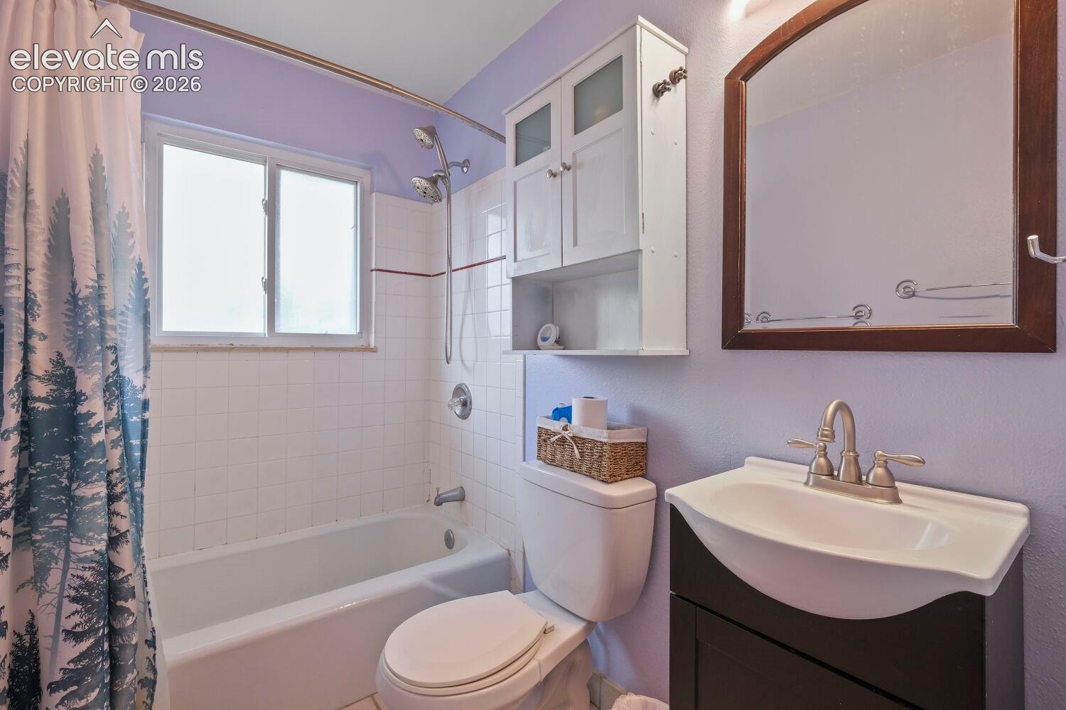 Full bathroom featuring a window, white subway tile shower surround, shower/tub combination, and a contemporary vanity with an integrated sink
