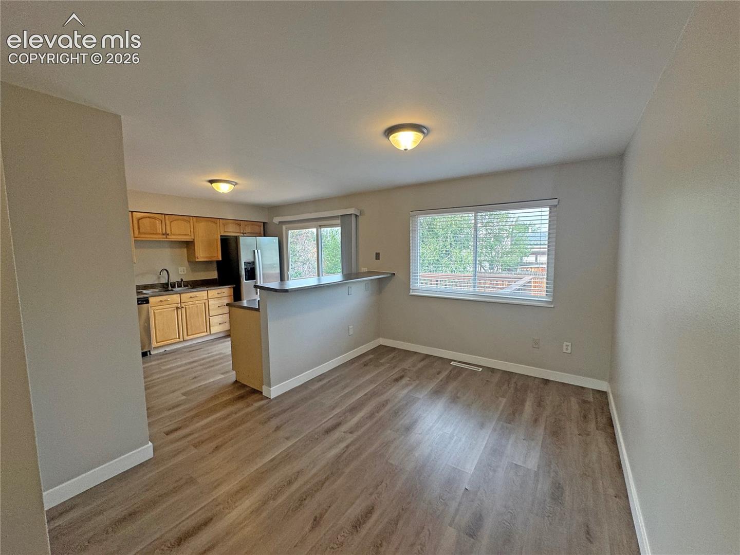 Kitchen featuring wood-finish cabinetry, a peninsula with a breakfast bar, sliding glass door, large window, and wood-finish flooring