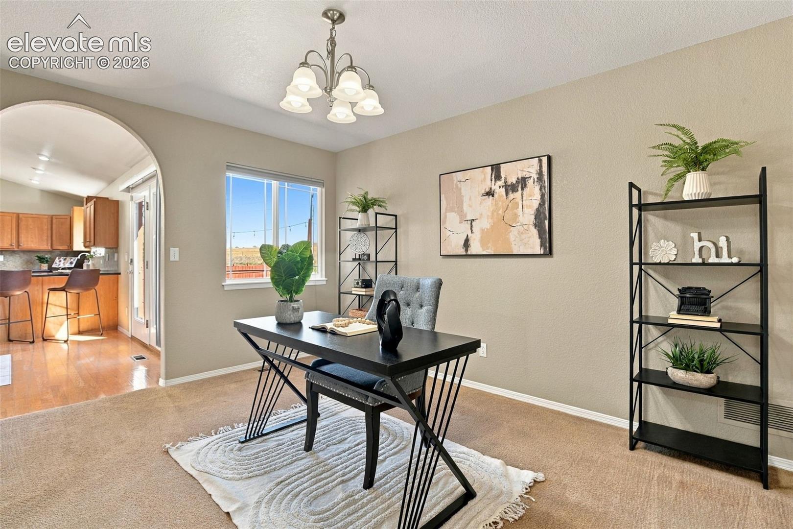 Recessed lighting, arched doorway, kitchen with wood-finish cabinetry, hard surface flooring, and a large window