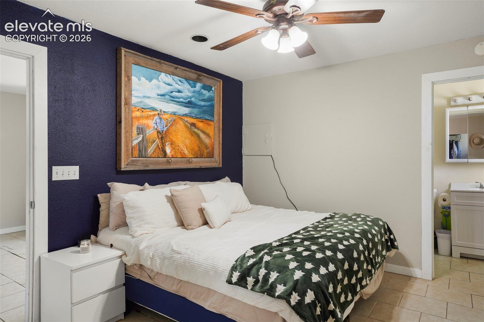 Ceiling fan with integrated lighting, recessed ceiling light, tile flooring, textured accent wall, and a full bathroom with a vanity sink