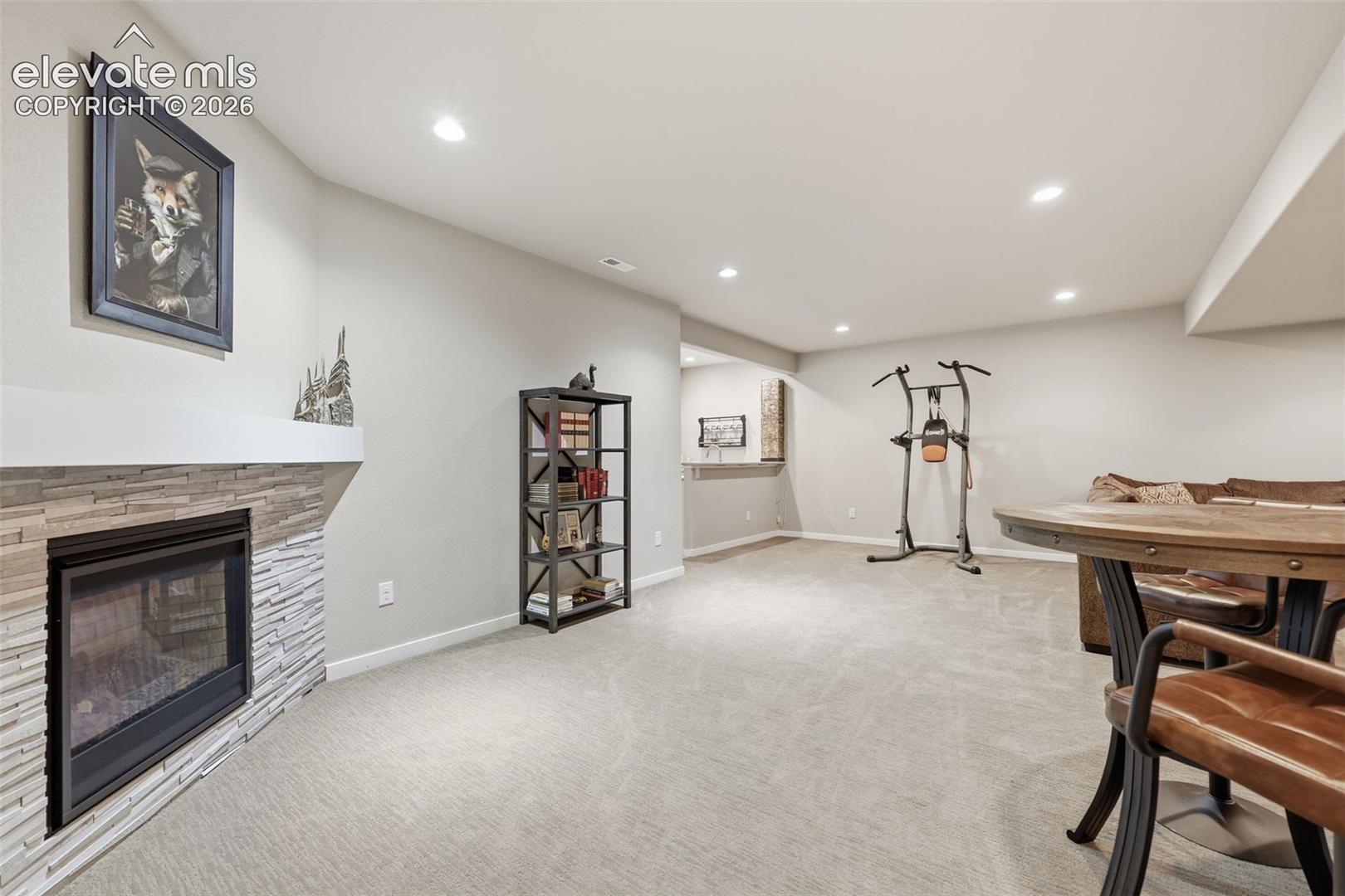 A fireplace with a stacked stone facade and mantel, recessed lighting.