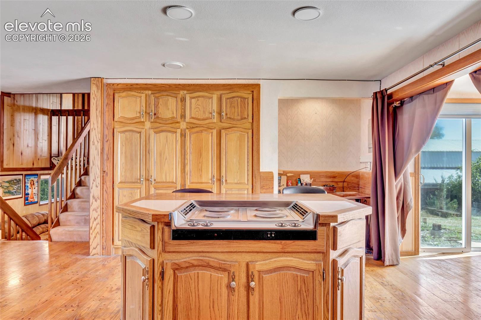 Central island cooktop, hardwood flooring, built-in cabinetry, sliding glass door, and recessed lighting