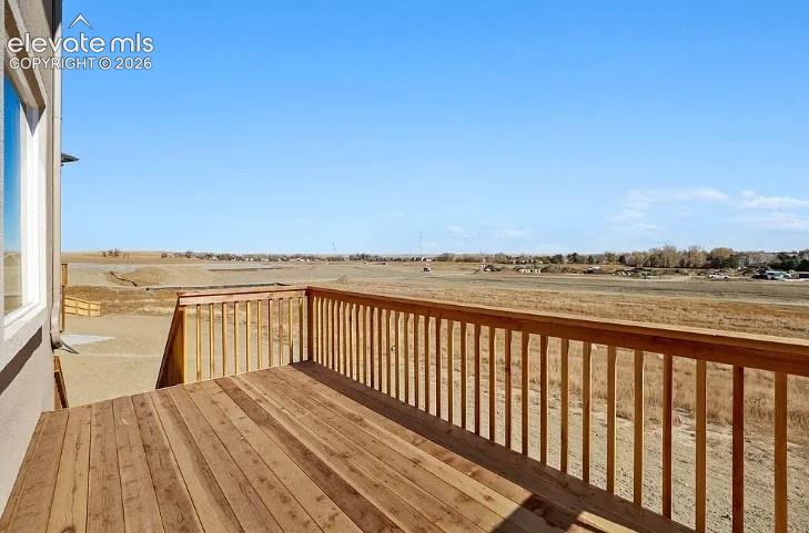 Elevated wood deck featuring vertical wood balusters and a wide expanse of open landscape