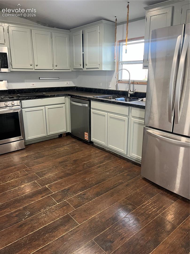 Spacious kitchen featuring wood-finish flooring, light-toned cabinetry, dark countertops, and stainless steel appliances