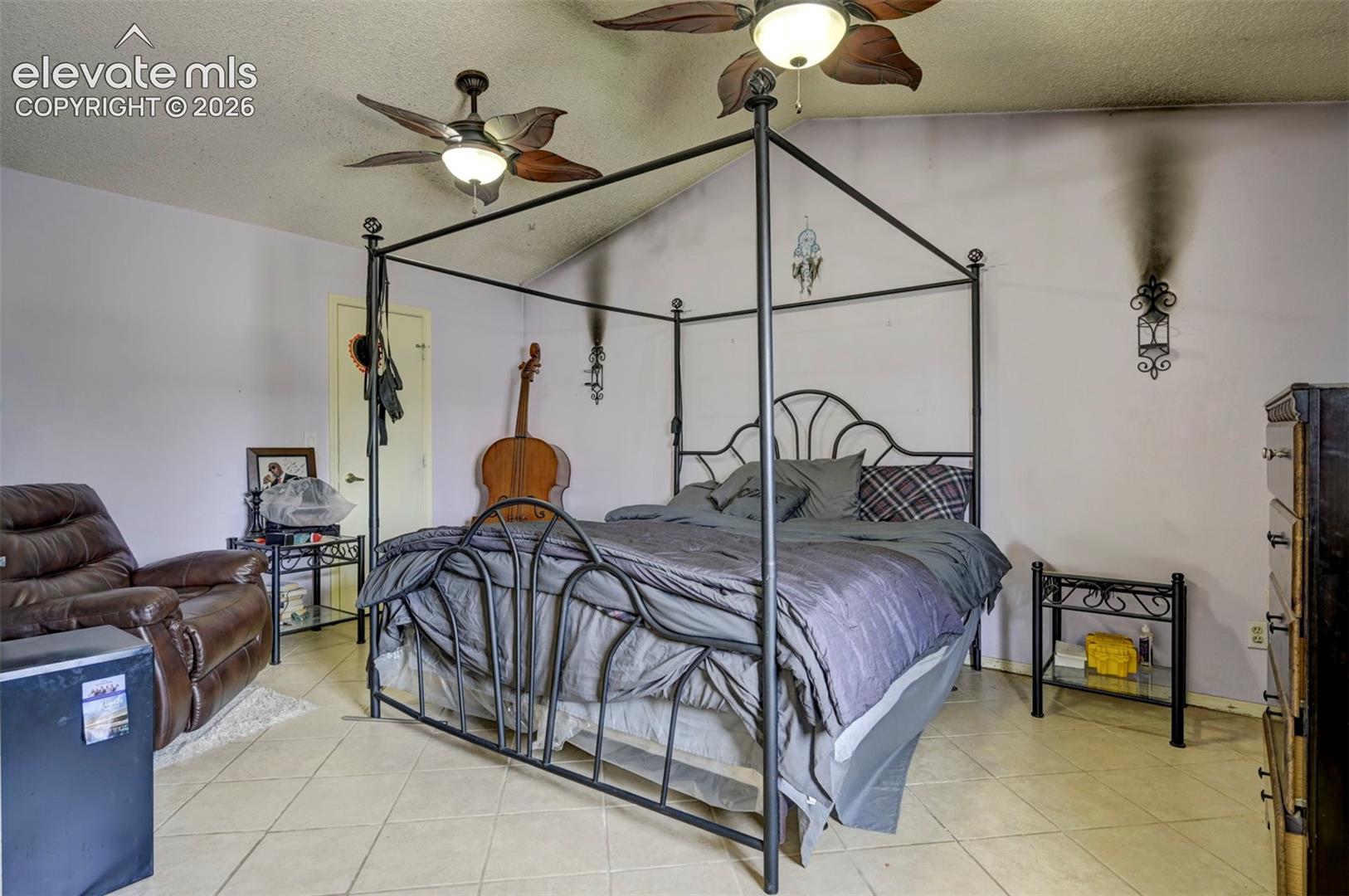 Spacious room featuring vaulted ceilings, ceiling fan light fixtures, and neutral tile flooring