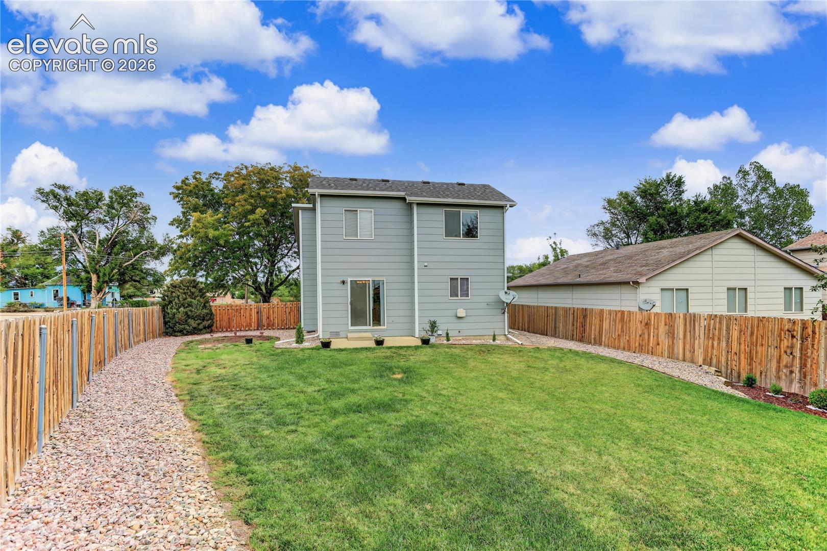Expansive backyard featuring a manicured lawn, a gravel path, and wood fencing