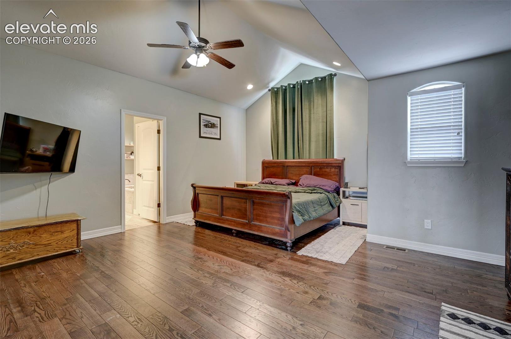 Vaulted primary bedroom with hardwood floors